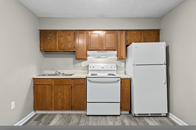 kitchen featuring sink, white appliances, light hardwood / wood-style flooring, and a textured ceiling