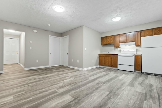 kitchen with sink, white appliances, light hardwood / wood-style floors, and a textured ceiling