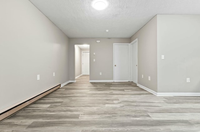 unfurnished room featuring a baseboard heating unit, light hardwood / wood-style floors, and a textured ceiling