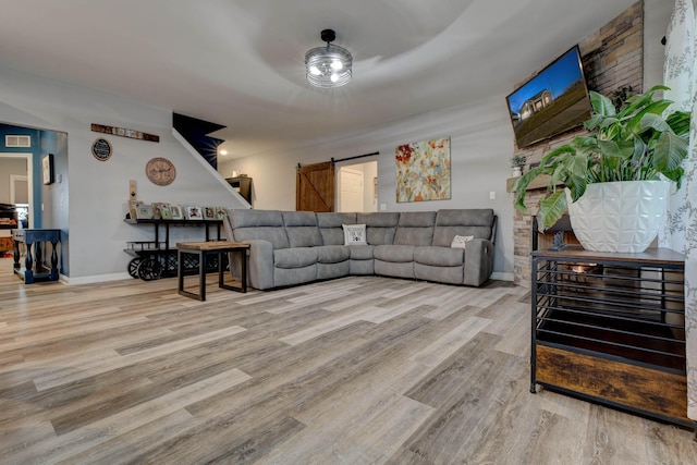 living room with a barn door and light hardwood / wood-style flooring