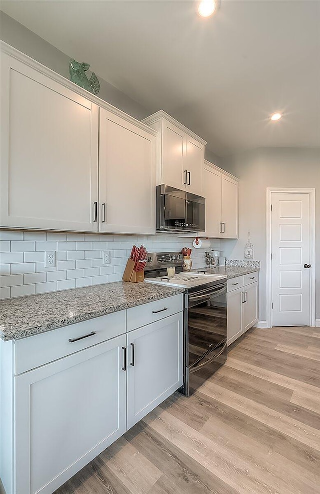 kitchen featuring electric range, black microwave, white cabinetry, and light wood-type flooring