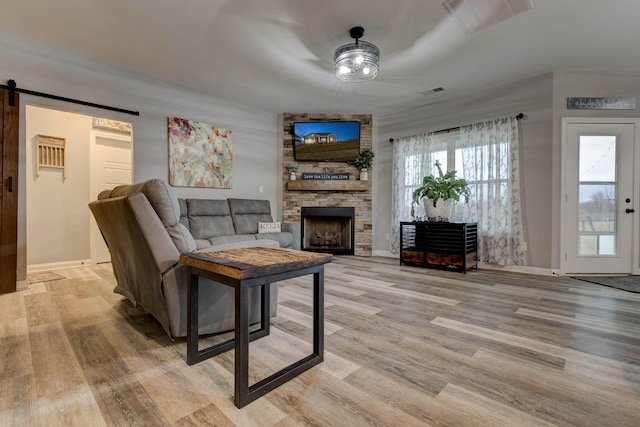 living room featuring a fireplace, a barn door, and light hardwood / wood-style floors