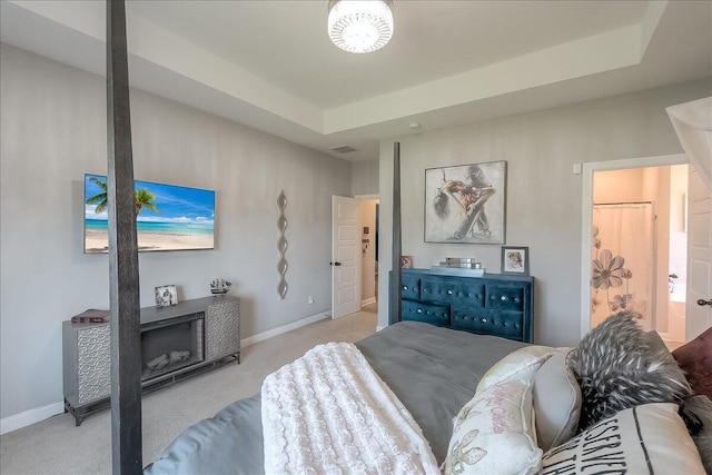 bedroom featuring baseboards, carpet floors, a raised ceiling, and connected bathroom