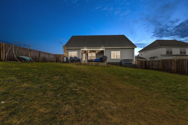 back house at dusk with a lawn and a patio area