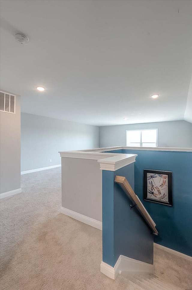 corridor with light colored carpet, baseboards, an upstairs landing, and visible vents
