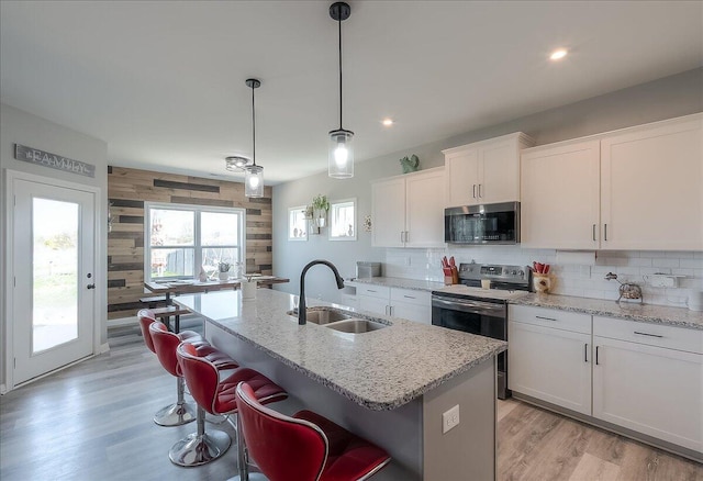 kitchen with tasteful backsplash, appliances with stainless steel finishes, white cabinetry, and a sink
