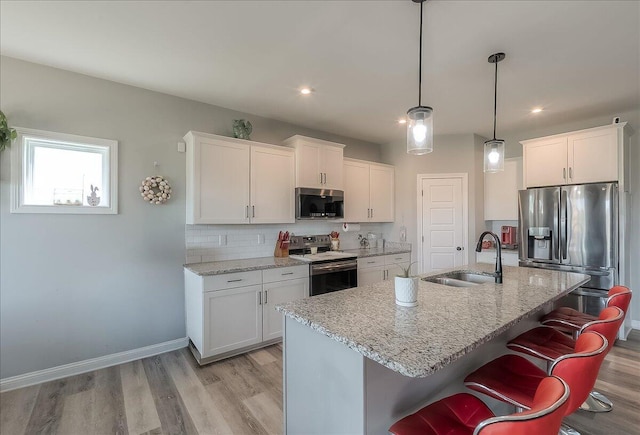 kitchen with appliances with stainless steel finishes, a sink, white cabinetry, and light wood-type flooring