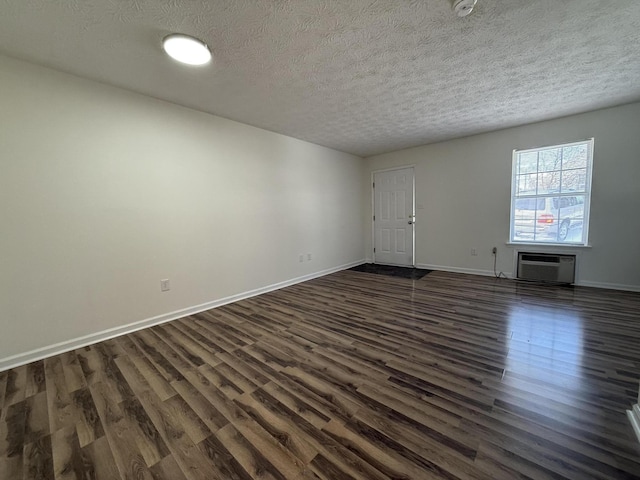 empty room featuring dark hardwood / wood-style flooring, a wall mounted AC, and a textured ceiling