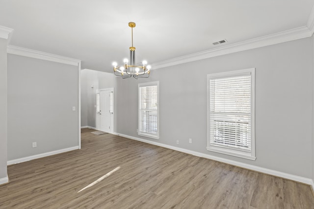 empty room with hardwood / wood-style flooring, ornamental molding, and a chandelier