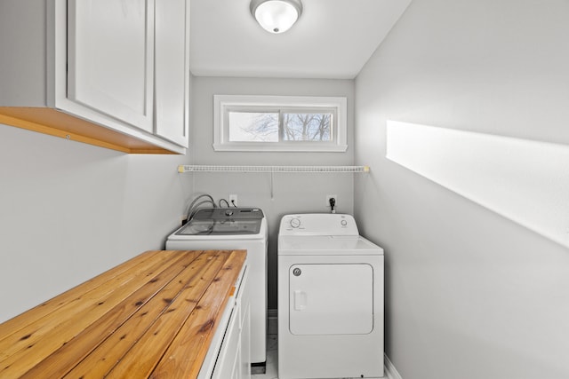 clothes washing area with separate washer and dryer and cabinets