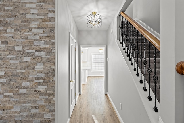 corridor featuring an inviting chandelier and light hardwood / wood-style floors