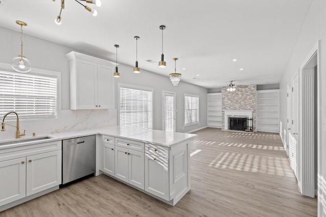 kitchen with stainless steel dishwasher, kitchen peninsula, sink, and white cabinets