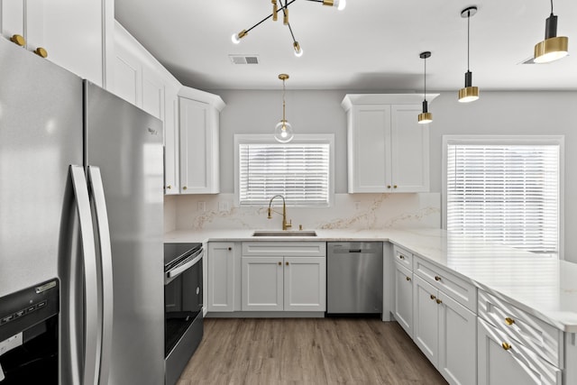 kitchen with pendant lighting, white cabinetry, appliances with stainless steel finishes, and sink