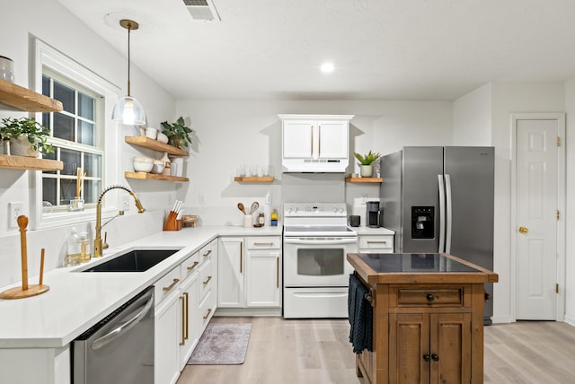 kitchen featuring sink, decorative light fixtures, stainless steel appliances, and white cabinets