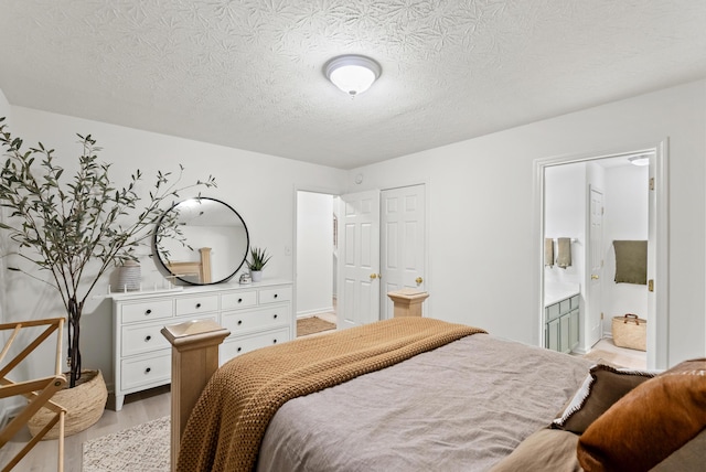 bedroom with connected bathroom, a textured ceiling, and light wood-type flooring