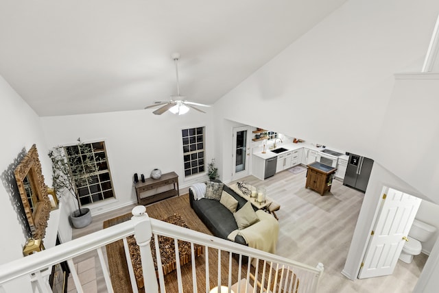 living room with high vaulted ceiling, sink, ceiling fan, and light hardwood / wood-style flooring