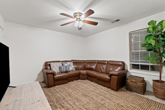 living room with a textured ceiling, light hardwood / wood-style floors, and ceiling fan