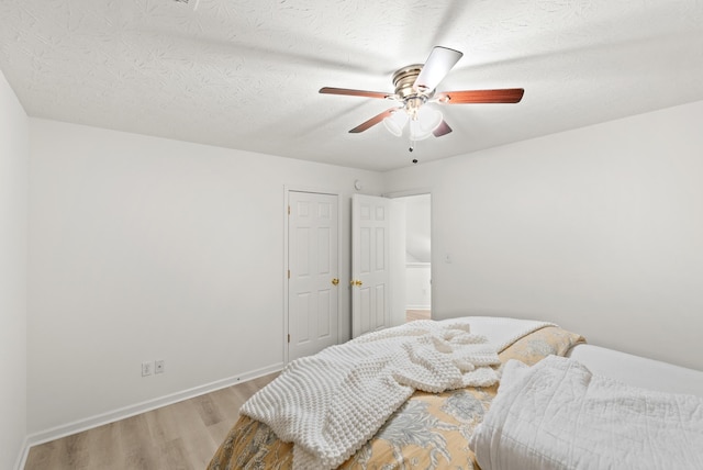 bedroom with ceiling fan, a textured ceiling, and light wood-type flooring