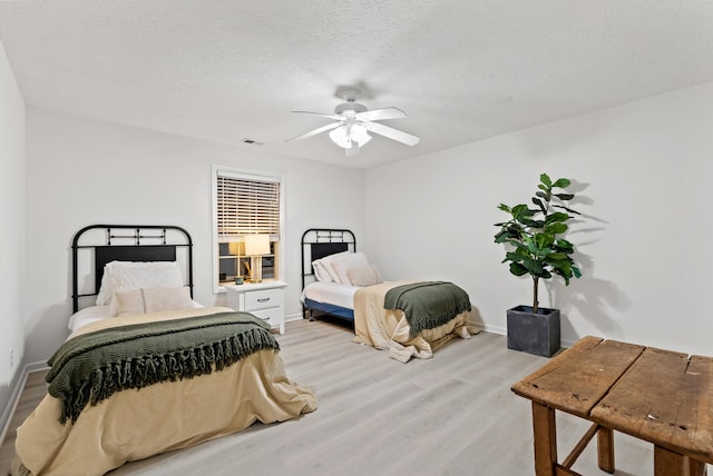 bedroom featuring ceiling fan, a textured ceiling, and light hardwood / wood-style floors