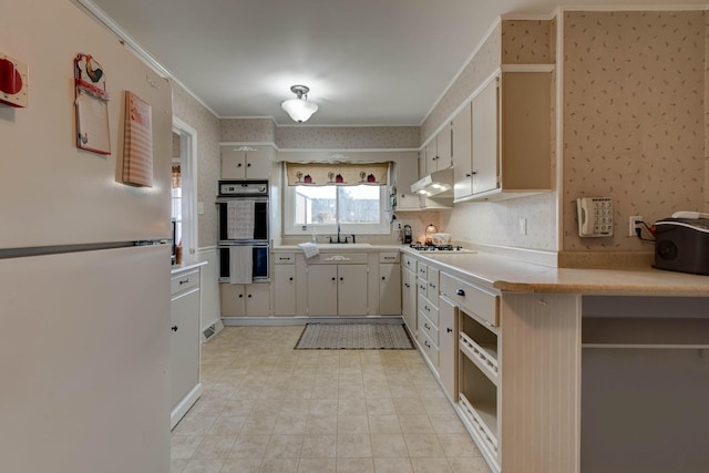 kitchen featuring white appliances, ornamental molding, sink, and white cabinets
