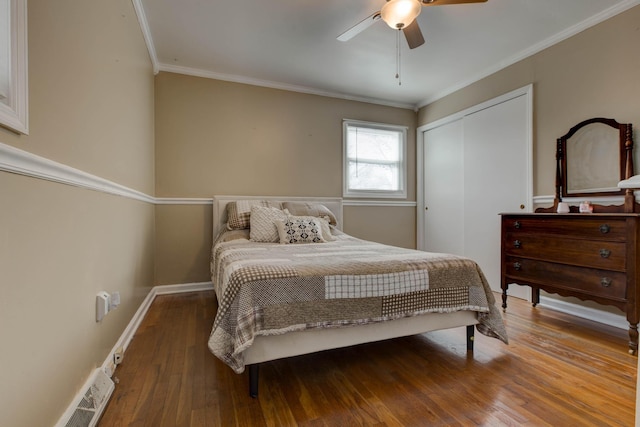 bedroom with wood-type flooring, ceiling fan, crown molding, and a closet