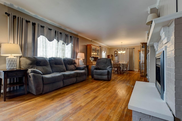 living room with hardwood / wood-style flooring, a fireplace, ornamental molding, and a chandelier