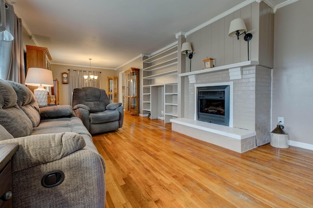 living room featuring light hardwood / wood-style flooring, a notable chandelier, a fireplace, and ornamental molding