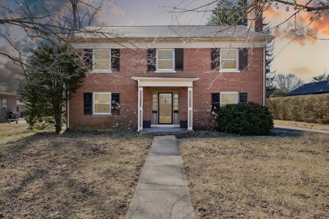 view of front of home with a lawn and brick siding