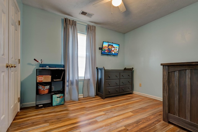 bedroom featuring ceiling fan, a textured ceiling, and light wood-type flooring