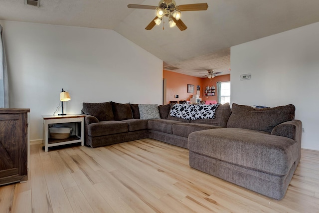 living room with lofted ceiling, ceiling fan, and light wood-type flooring