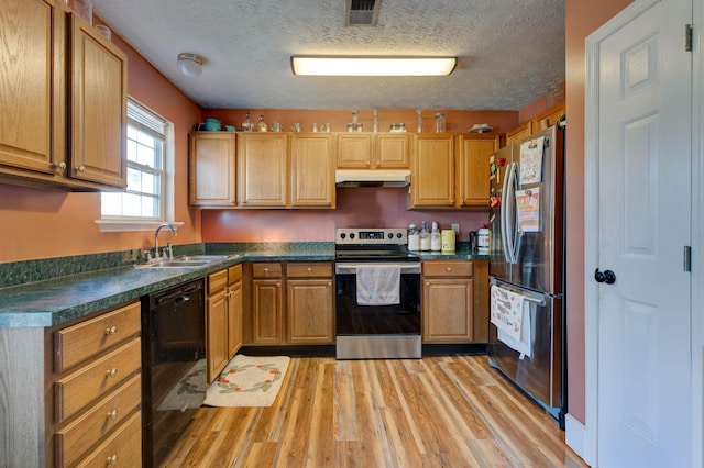 kitchen with sink, stainless steel appliances, a textured ceiling, and light wood-type flooring