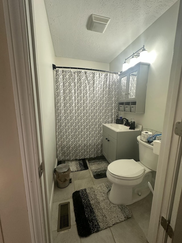 bathroom featuring toilet, a textured ceiling, tile patterned flooring, and visible vents