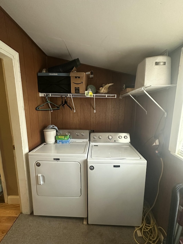 washroom featuring laundry area, separate washer and dryer, and wood walls