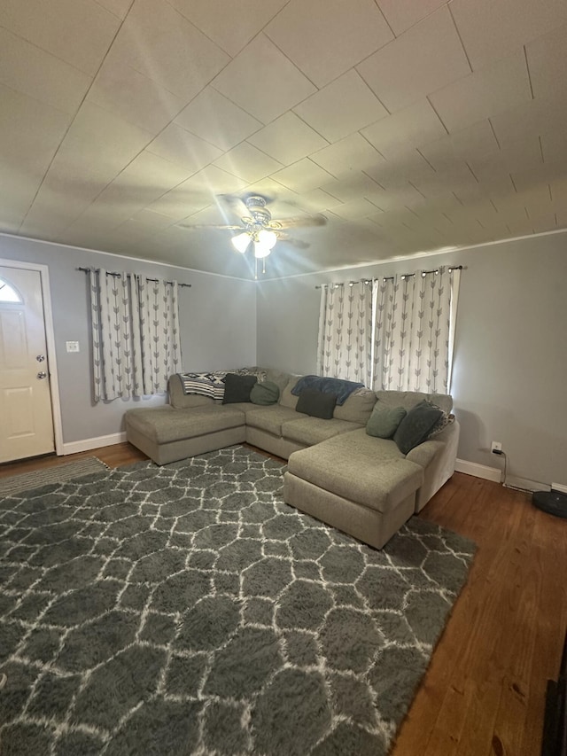 living room with ceiling fan, baseboards, and wood finished floors