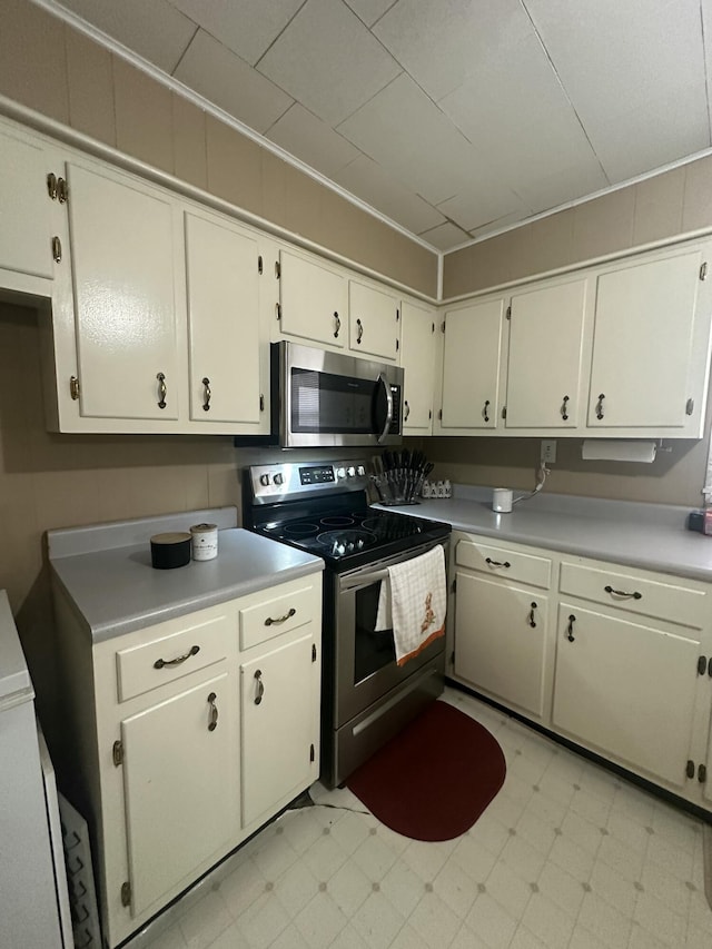 kitchen featuring appliances with stainless steel finishes, light countertops, ornamental molding, and light floors