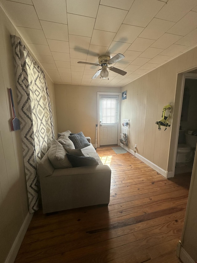 living room with baseboards, hardwood / wood-style flooring, and a ceiling fan