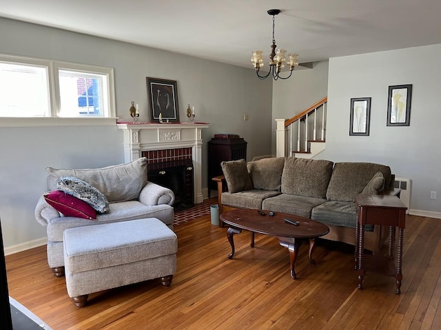 living room featuring a brick fireplace, wood-type flooring, radiator, and a chandelier