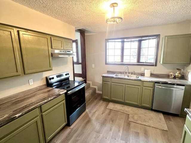 kitchen with under cabinet range hood, appliances with stainless steel finishes, green cabinets, and a sink