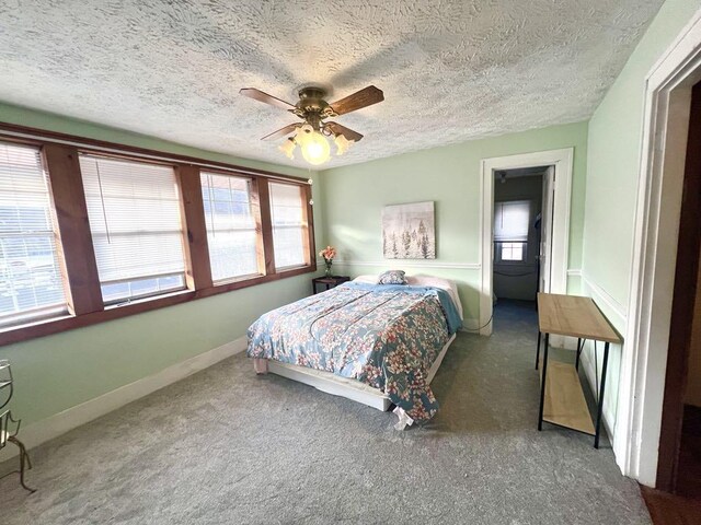 bedroom featuring dark colored carpet, ceiling fan, a textured ceiling, and baseboards