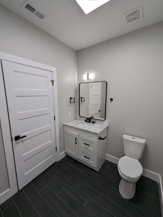 bathroom featuring vanity, wood-type flooring, and toilet