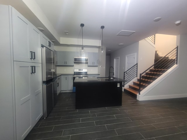 kitchen featuring range hood, sink, hanging light fixtures, stainless steel appliances, and a center island with sink