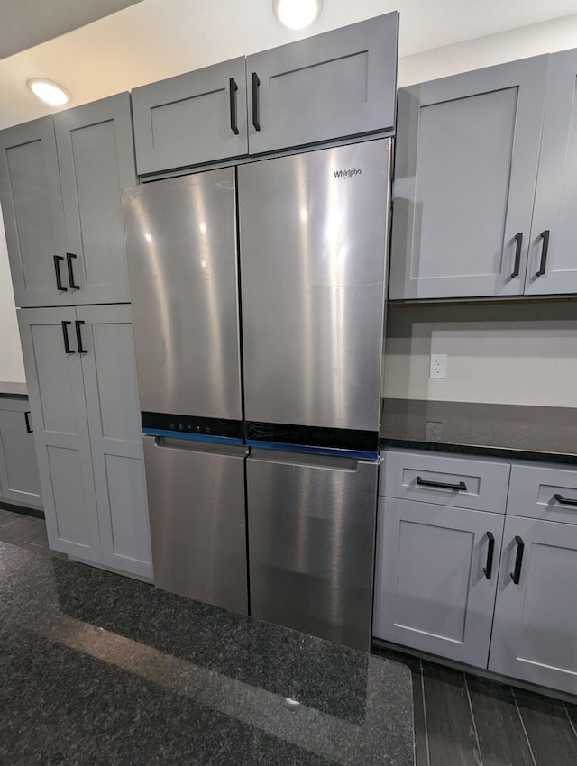 interior details with gray cabinetry, stainless steel refrigerator, and dark stone counters