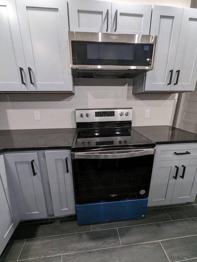 kitchen featuring stainless steel appliances, dark stone counters, and white cabinets