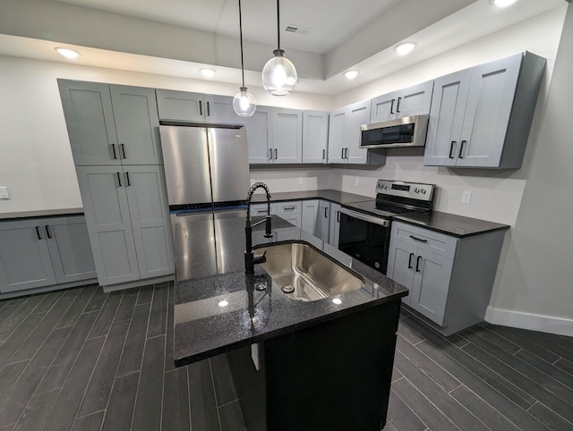 kitchen with pendant lighting, sink, appliances with stainless steel finishes, gray cabinetry, and dark stone countertops