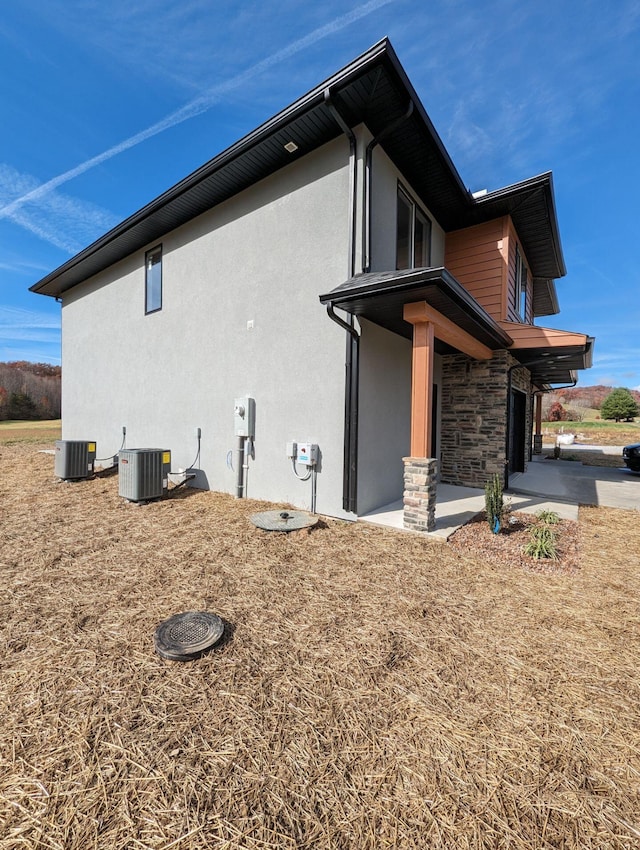 view of side of property with cooling unit and a patio