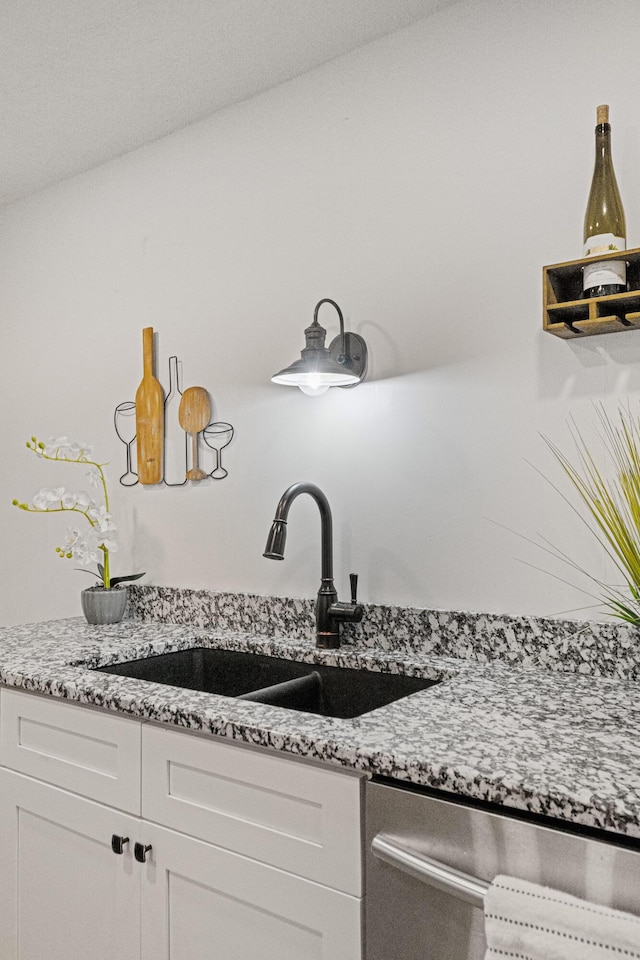 kitchen with white cabinetry, dishwasher, sink, and light stone countertops