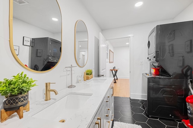 bathroom featuring stacked washer and dryer, vanity, and tile patterned flooring