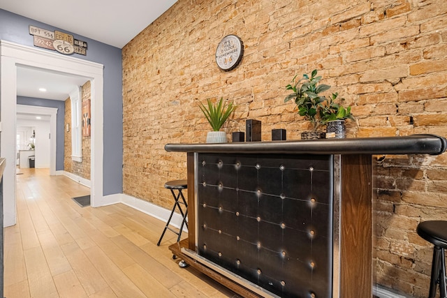 bar featuring hardwood / wood-style flooring and brick wall