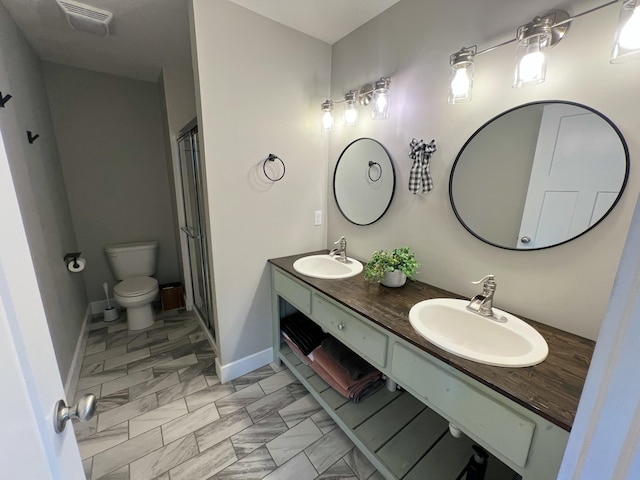 bathroom featuring vanity, a shower with shower door, and toilet