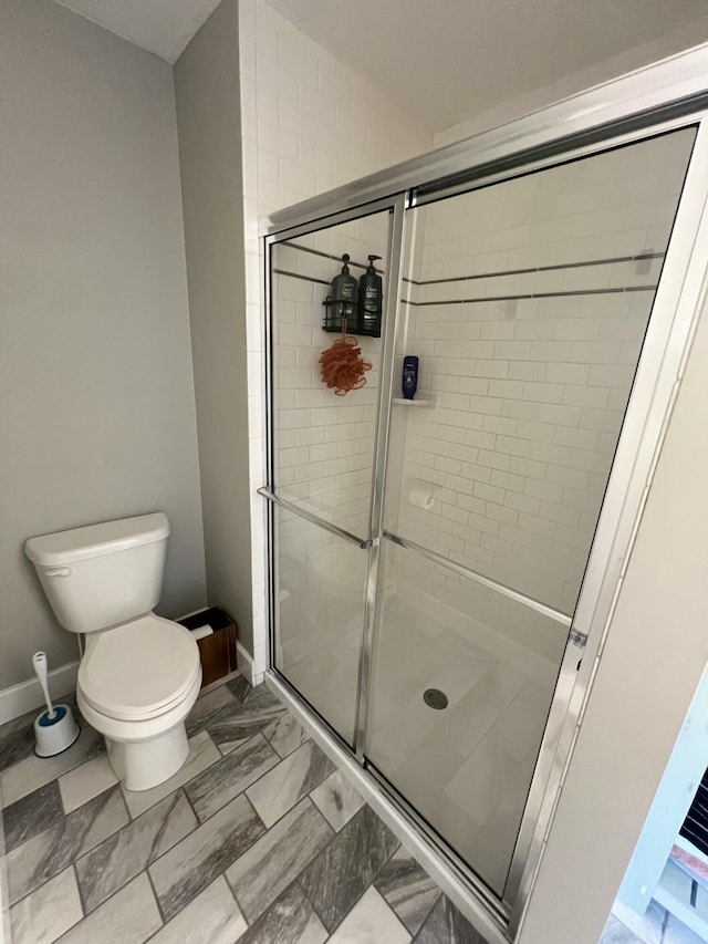 bathroom with a shower with shower door and toilet